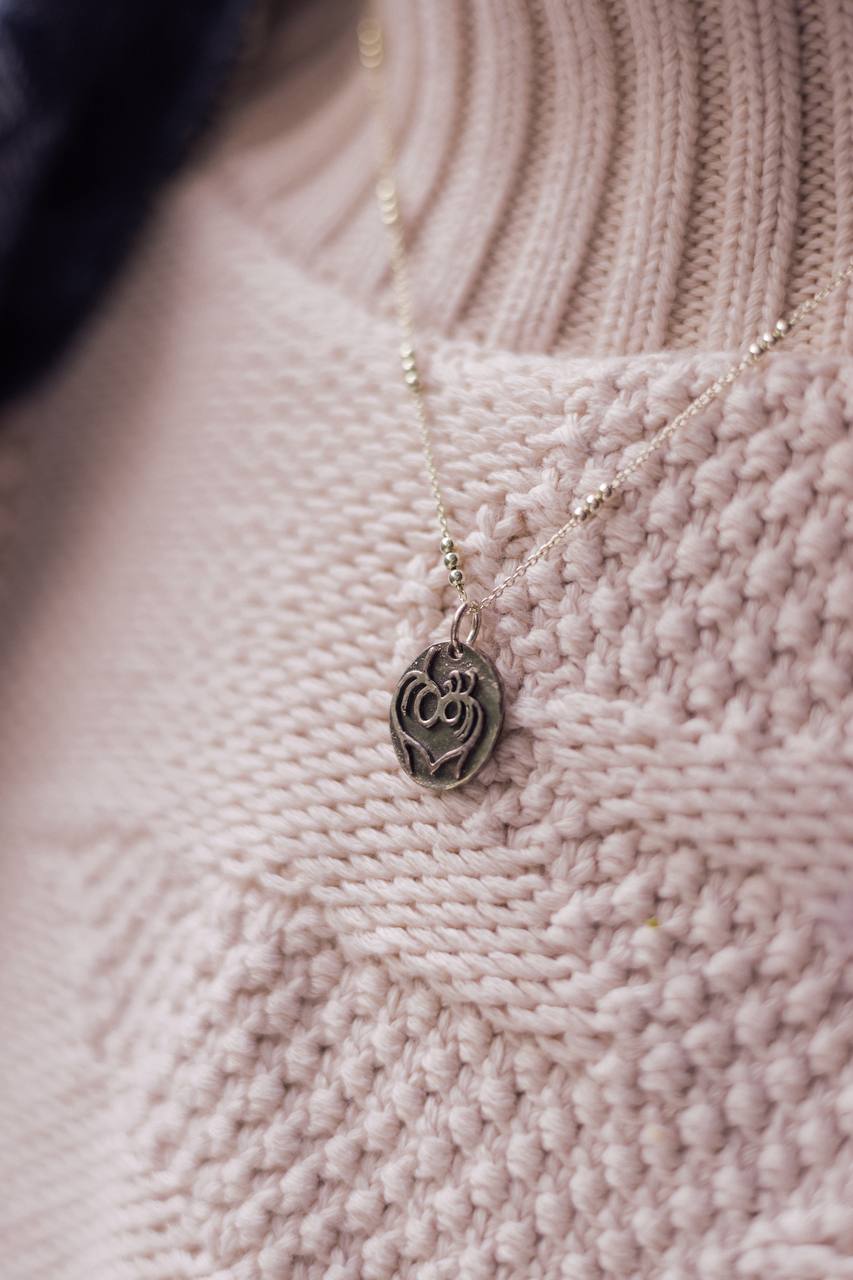 Objects pendant close-up in soft pink knitwear